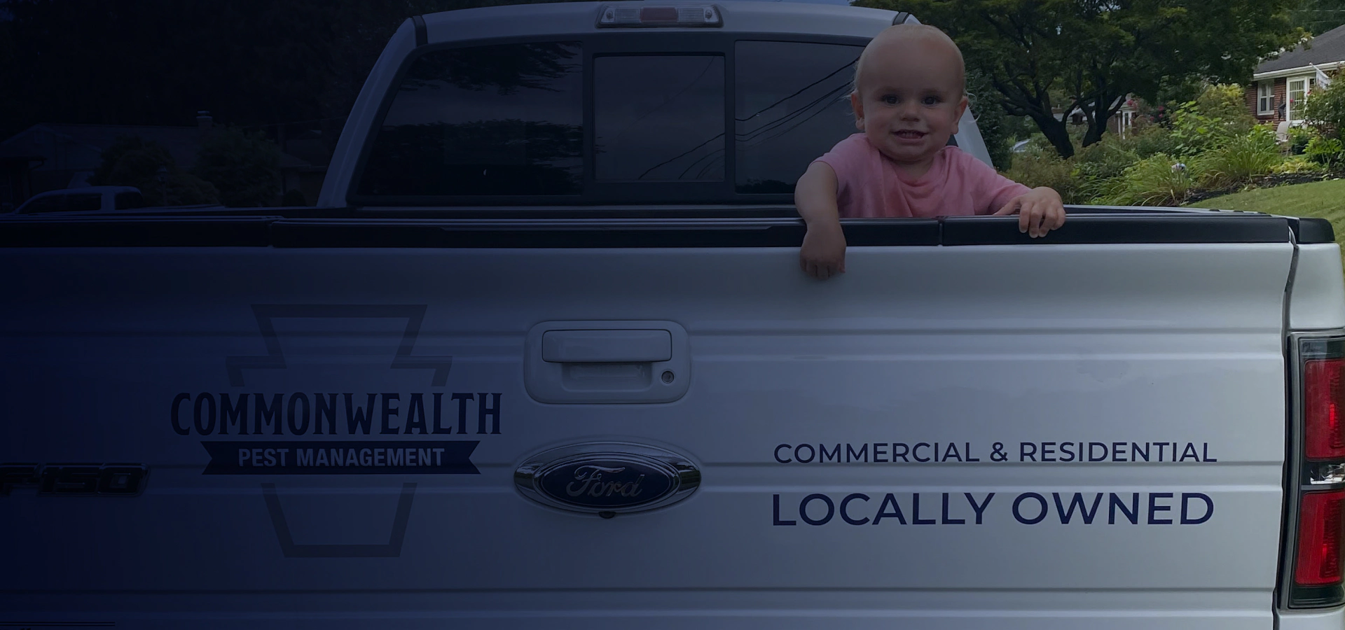 young child standing in bed of white truck with company info on back